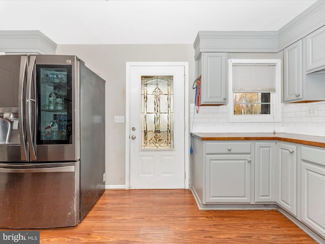 kitchen featuring light hardwood / wood-style floors, butcher block counters, backsplash, and stainless steel fridge