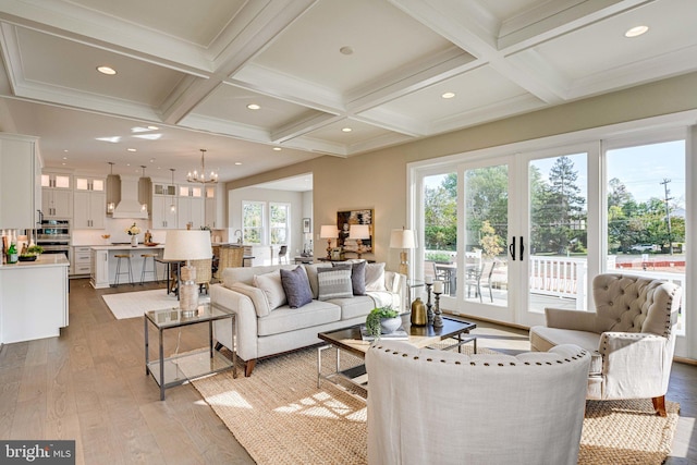 living room featuring light hardwood / wood-style floors, beam ceiling, a healthy amount of sunlight, and coffered ceiling