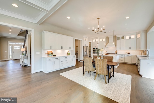 kitchen with custom exhaust hood, a kitchen island, white cabinetry, wood-type flooring, and sink