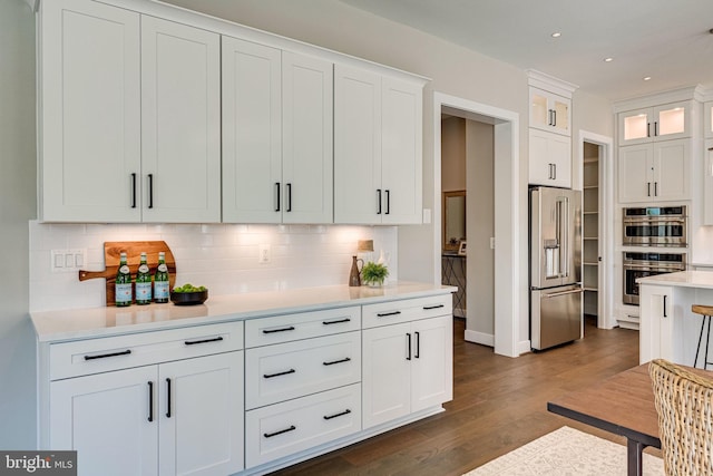 kitchen featuring dark wood finished floors, light countertops, backsplash, appliances with stainless steel finishes, and white cabinetry