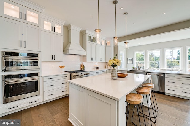 kitchen featuring custom exhaust hood, a sink, a peninsula, appliances with stainless steel finishes, and dark wood-type flooring