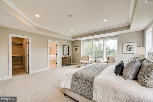 carpeted bedroom with ensuite bathroom, a raised ceiling, crown molding, and a walk in closet