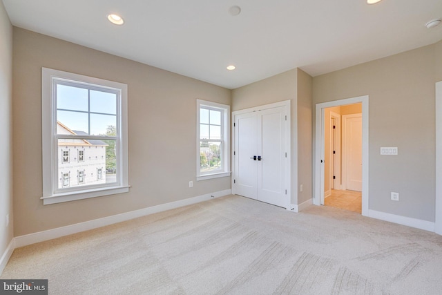 unfurnished bedroom with a closet, light carpet, and multiple windows