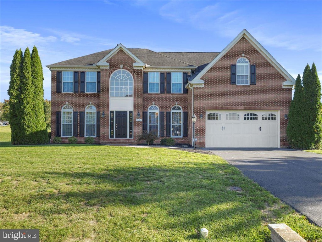 colonial-style house featuring a front yard and a garage