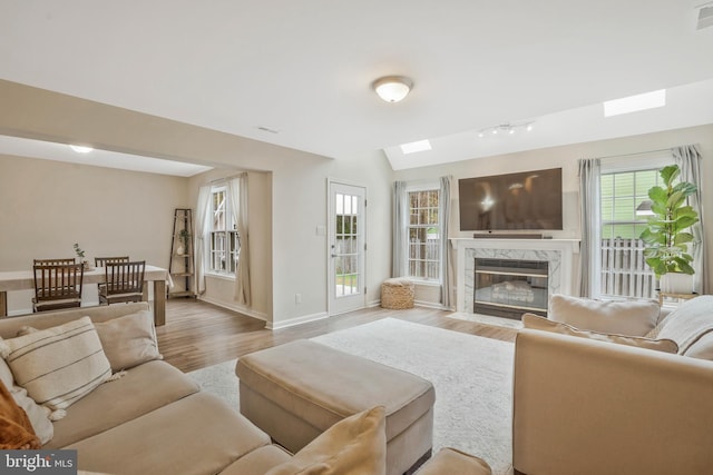 living room with lofted ceiling, light hardwood / wood-style floors, and a premium fireplace