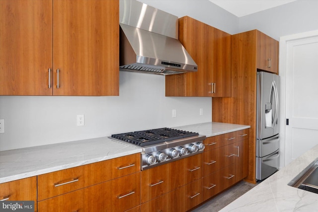 kitchen featuring light stone countertops, wall chimney exhaust hood, and appliances with stainless steel finishes