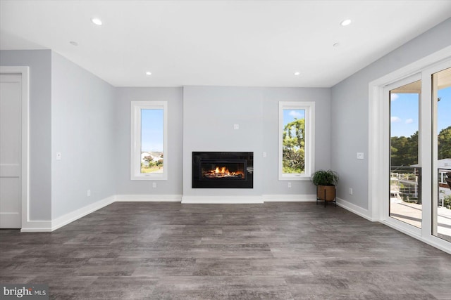 unfurnished living room featuring dark hardwood / wood-style flooring and a wealth of natural light