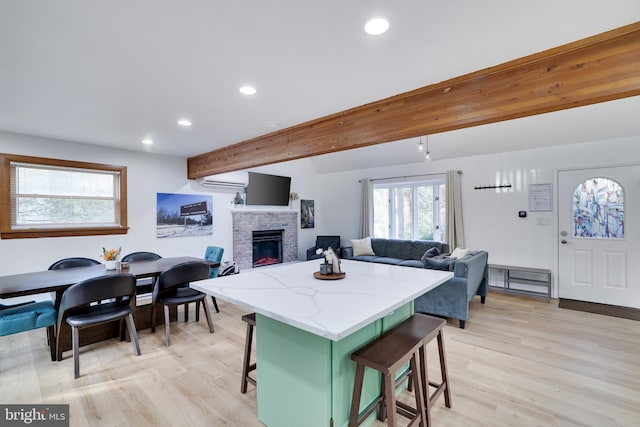 kitchen with light hardwood / wood-style floors, a breakfast bar, green cabinetry, and a brick fireplace