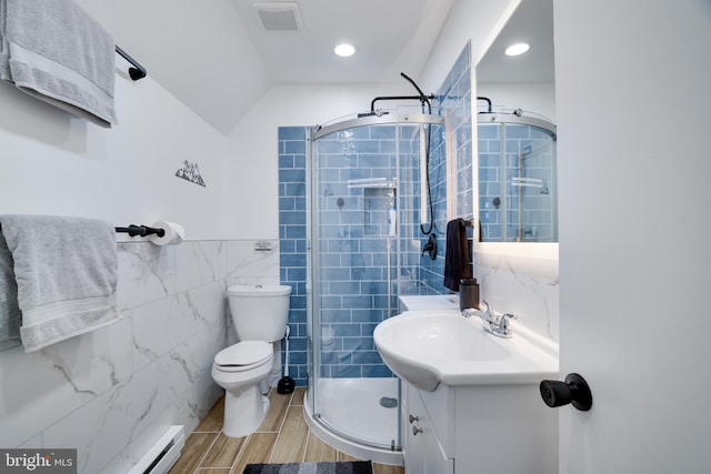 bathroom with toilet, a baseboard heating unit, vanity, tile walls, and an enclosed shower