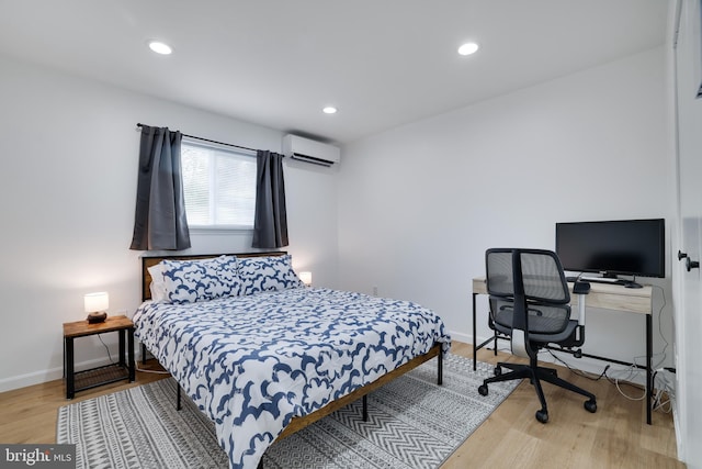 bedroom with light hardwood / wood-style floors and a wall unit AC