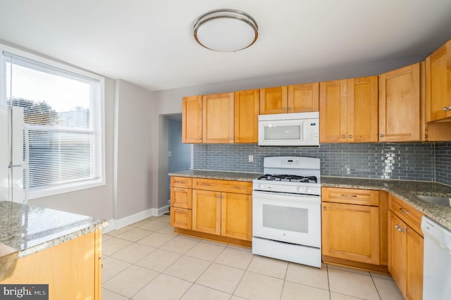 kitchen featuring stone counters, light tile patterned flooring, white appliances, and tasteful backsplash