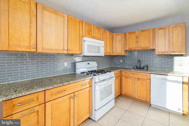 kitchen with decorative backsplash, sink, light tile patterned flooring, light stone counters, and white appliances