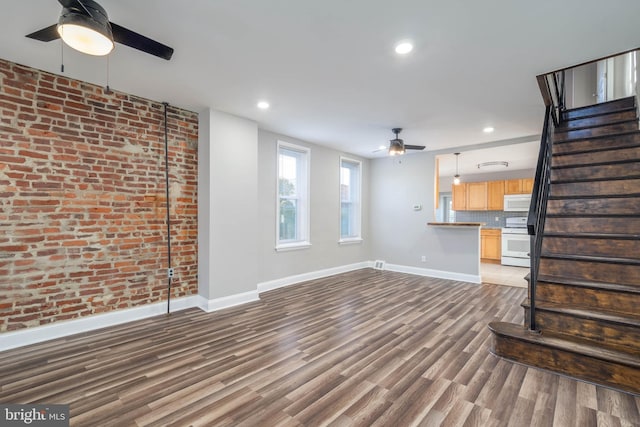 unfurnished living room with brick wall and hardwood / wood-style floors