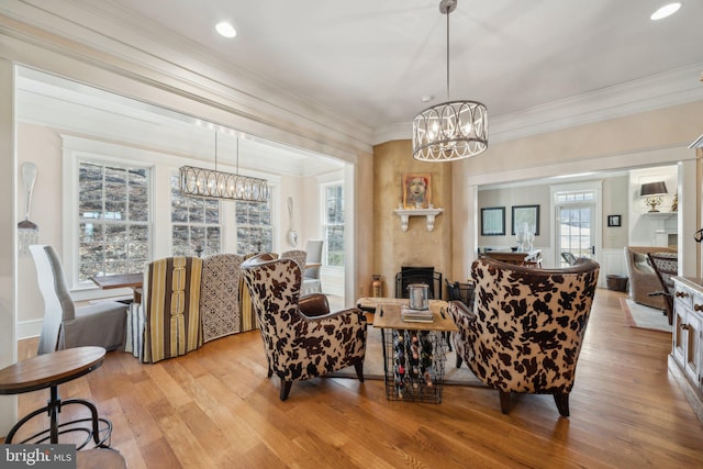 living room with light hardwood / wood-style floors, crown molding, and a notable chandelier