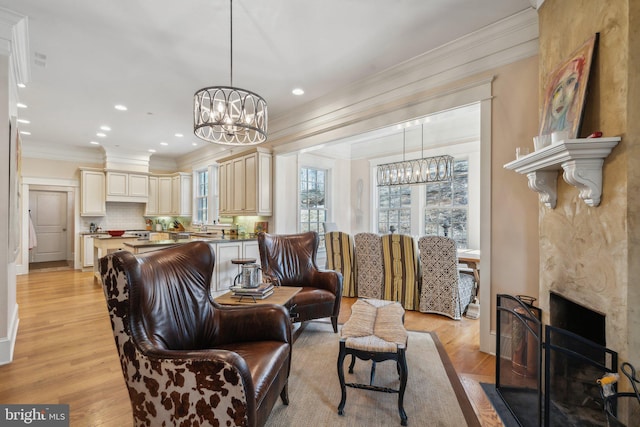 living room with light hardwood / wood-style floors, crown molding, and a notable chandelier