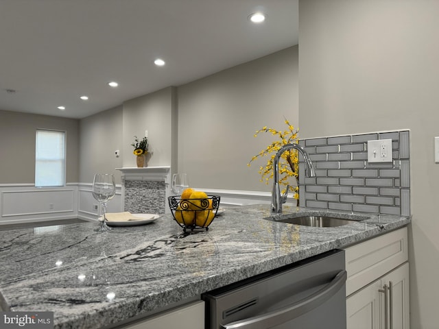 kitchen featuring decorative backsplash, stone counters, dishwasher, and sink