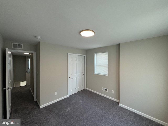 unfurnished bedroom featuring dark carpet and a closet