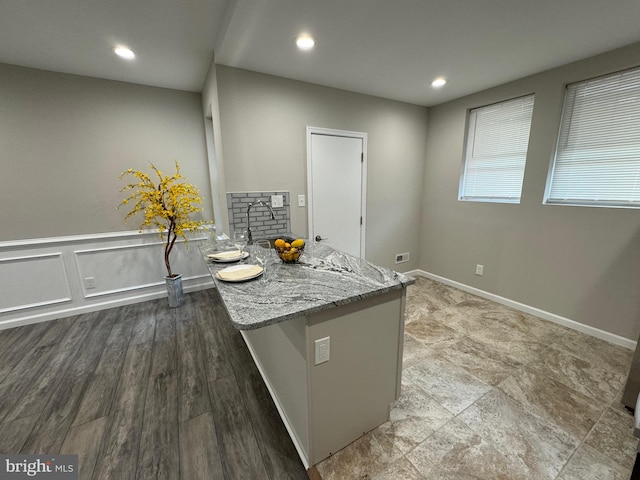 kitchen featuring light stone countertops, a kitchen island, and wood-type flooring