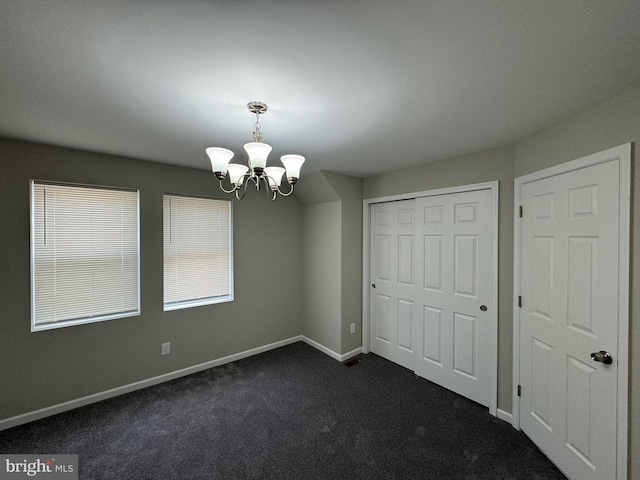 interior space featuring dark colored carpet, a closet, and a notable chandelier