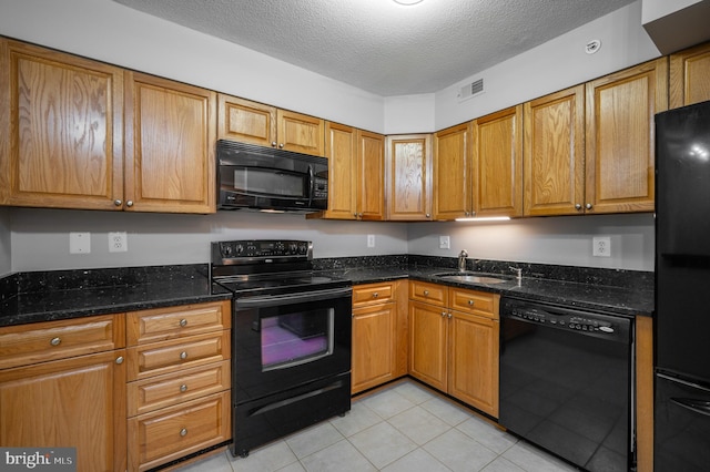 kitchen with black appliances, sink, a textured ceiling, dark stone countertops, and light tile patterned floors