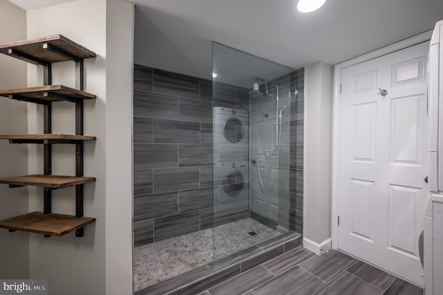 bathroom with a shower with door and stacked washer and clothes dryer