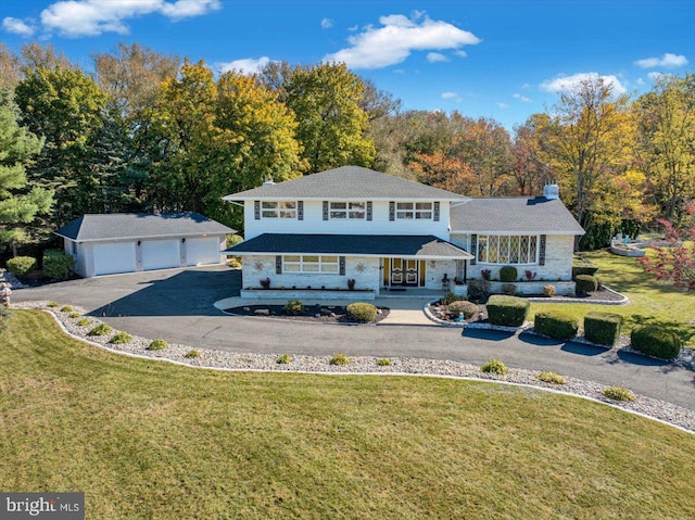 view of front of home featuring a front yard, an outdoor structure, a garage, and a porch