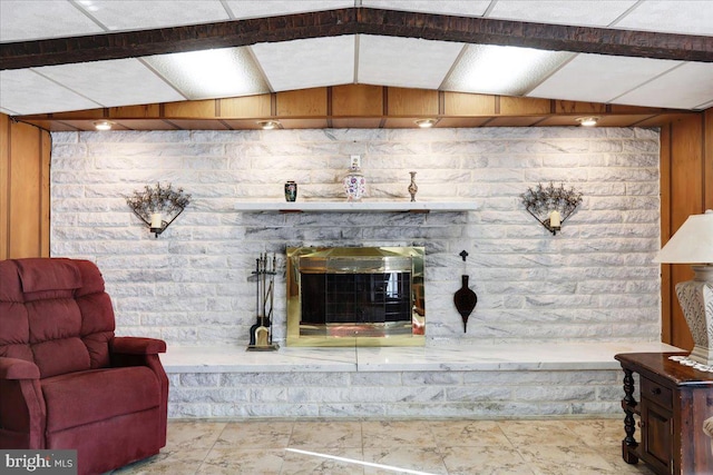 living room with wooden walls, vaulted ceiling with beams, and a fireplace