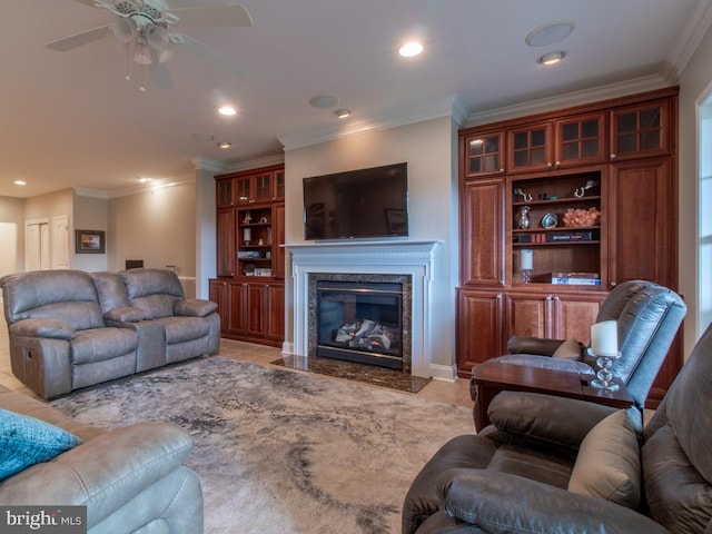 tiled living room with ceiling fan, crown molding, and a fireplace