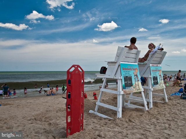 view of playground with a water view and a beach view