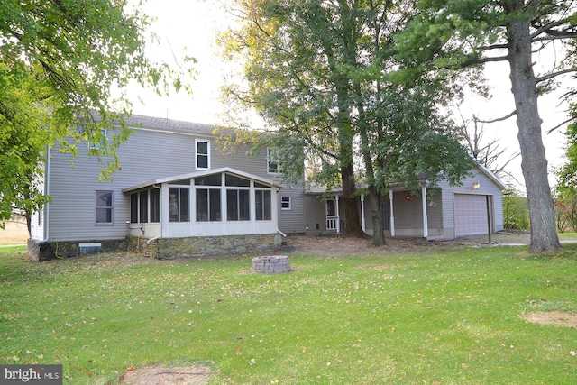 rear view of property featuring a yard, a garage, and a sunroom