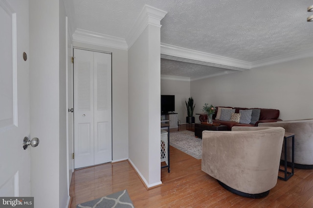 living room featuring crown molding, hardwood / wood-style floors, and a textured ceiling