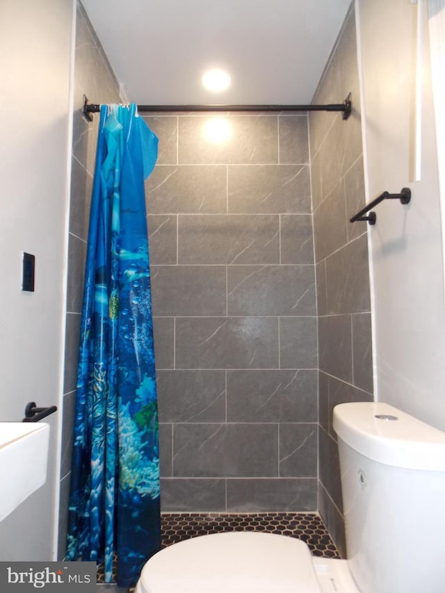 bathroom with a shower with shower curtain and toilet