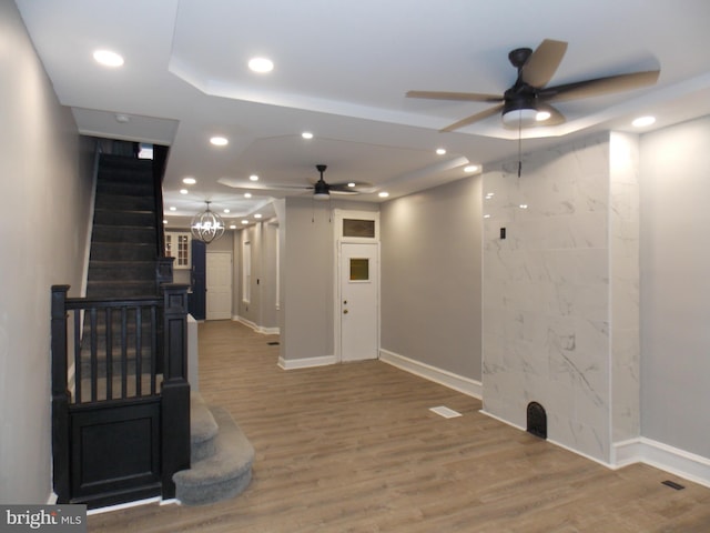 interior space featuring wood-type flooring and ceiling fan with notable chandelier