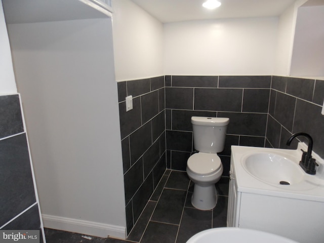 bathroom with tile walls, vanity, tile patterned floors, and toilet