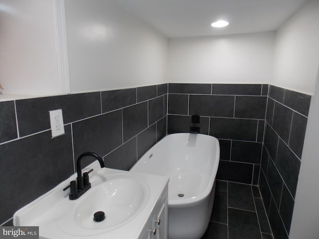 bathroom featuring tile walls, vanity, and a tub