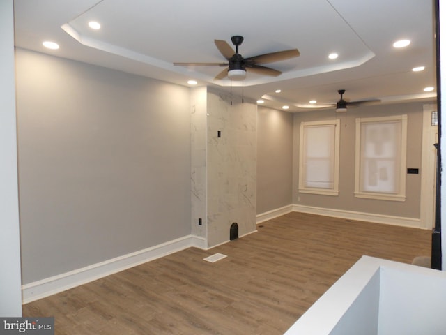 unfurnished room with dark wood-type flooring, ceiling fan, and a tray ceiling