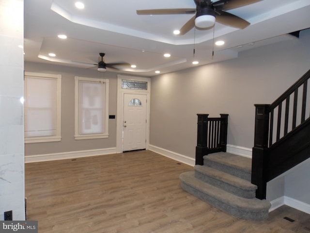 entrance foyer featuring ceiling fan, wood-type flooring, and a raised ceiling