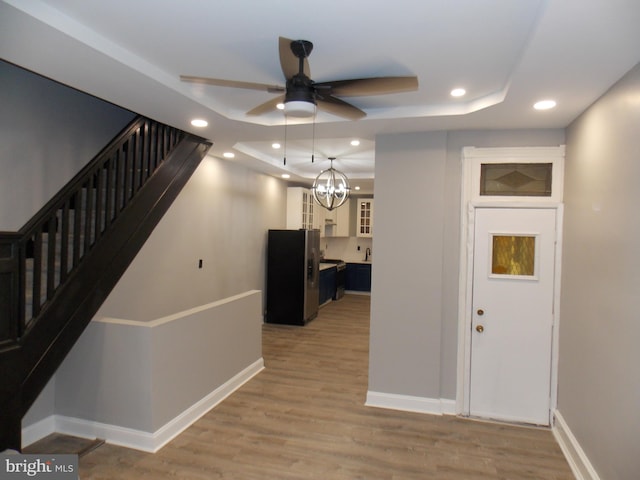 interior space with a chandelier, wood-type flooring, and a raised ceiling