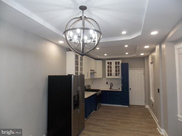 kitchen featuring white cabinetry, appliances with stainless steel finishes, hardwood / wood-style floors, a raised ceiling, and pendant lighting