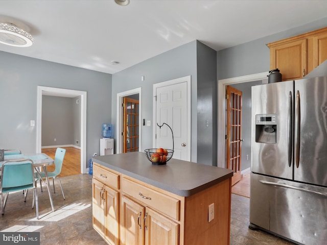 kitchen with light brown cabinetry, stainless steel fridge with ice dispenser, and a center island