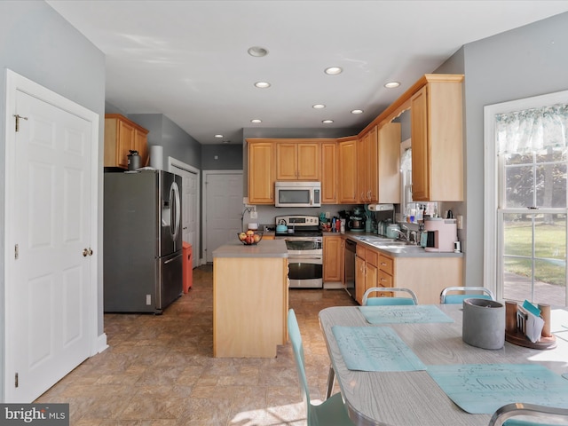 kitchen featuring sink, light brown cabinets, stainless steel appliances, and a center island