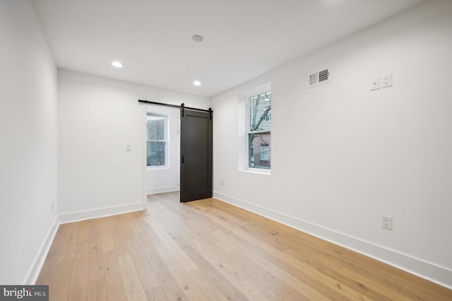 unfurnished bedroom featuring light hardwood / wood-style floors and a barn door