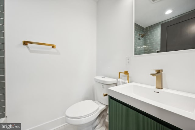 bathroom featuring toilet, vanity, and tiled shower