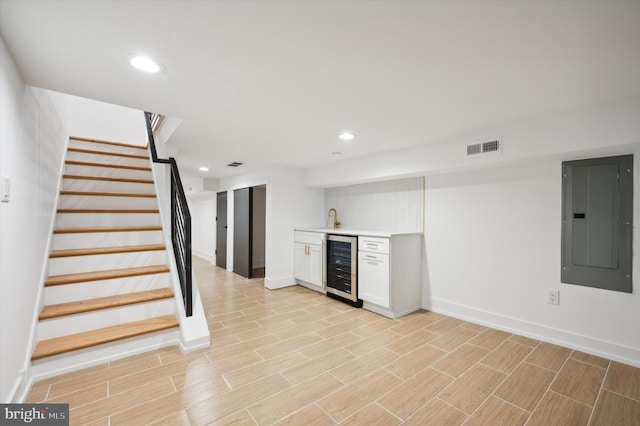 kitchen with wine cooler, sink, electric panel, and white cabinetry