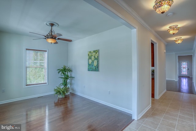 spare room featuring crown molding, light wood-type flooring, and ceiling fan