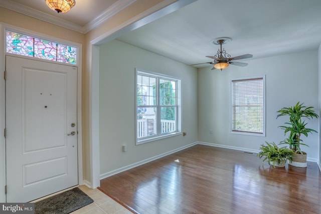 foyer featuring crown molding, light wood-type flooring, a healthy amount of sunlight, and ceiling fan