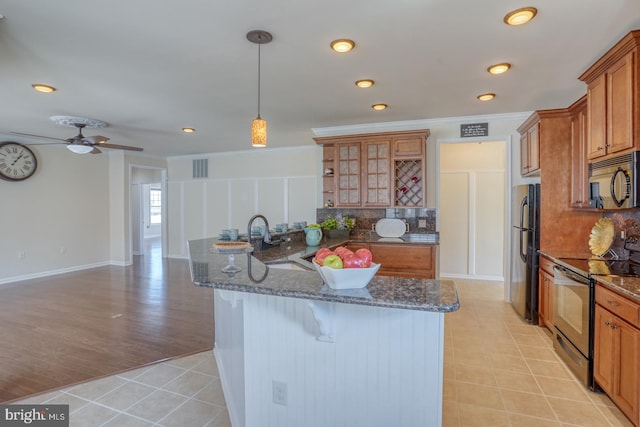 kitchen featuring sink, a kitchen bar, decorative light fixtures, appliances with stainless steel finishes, and light hardwood / wood-style floors