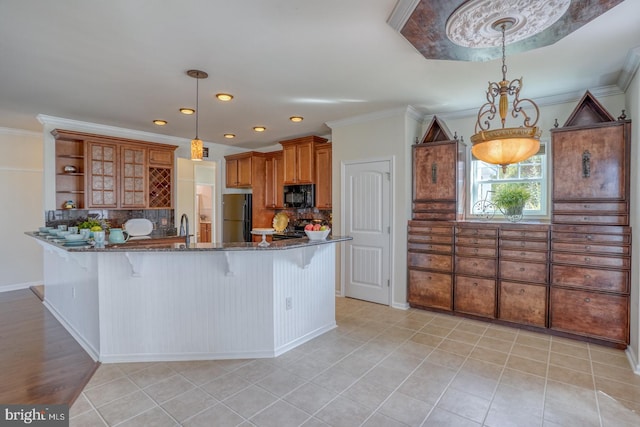 kitchen featuring a breakfast bar, decorative backsplash, decorative light fixtures, and stainless steel refrigerator