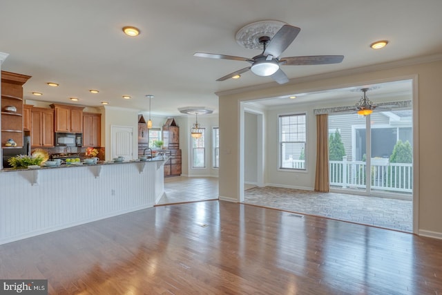 kitchen featuring hanging light fixtures, black appliances, plenty of natural light, and a kitchen breakfast bar