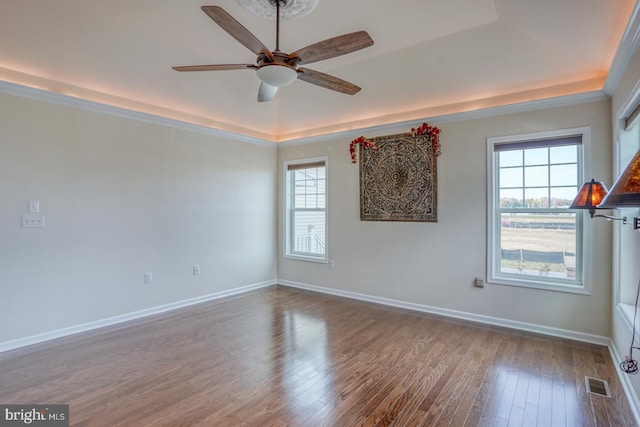 empty room featuring hardwood / wood-style floors, a raised ceiling, and ceiling fan